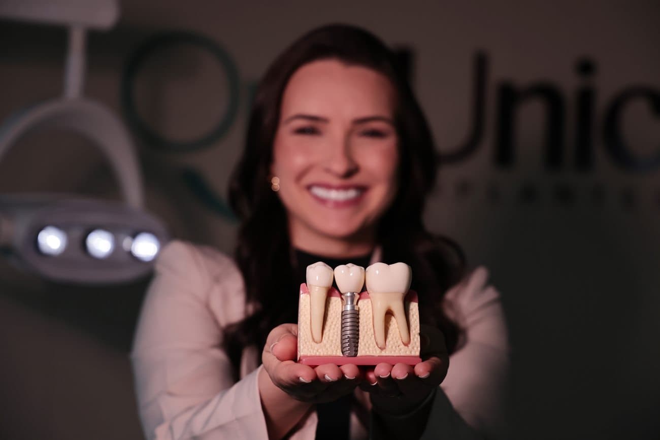 Dra. Keli Tessaro mostrando um modelo de implante dentário